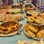 Buffet table of cakes, sandwiches and pastries.